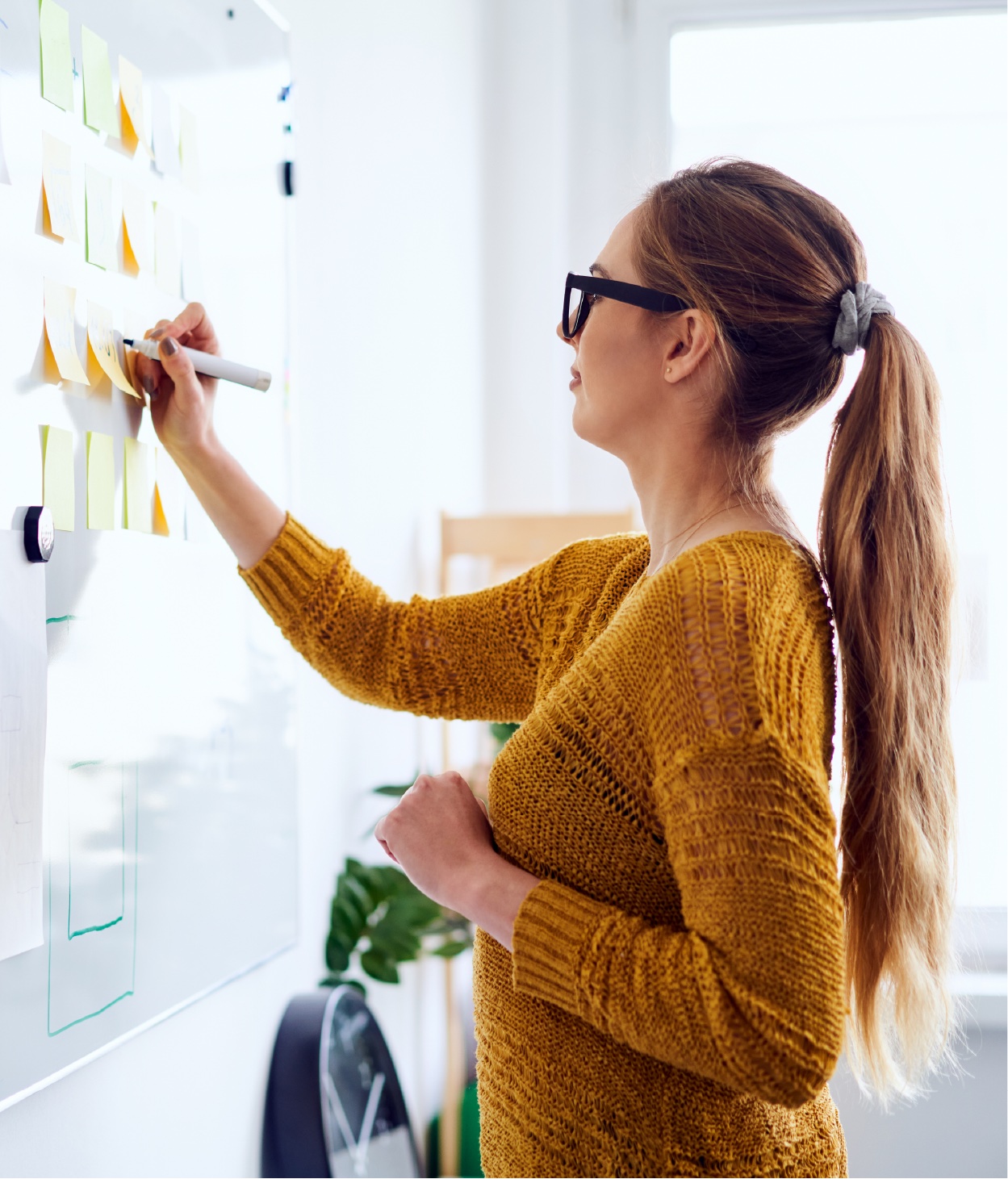 Woman making notes on a whiteboard during a brainstorming session.